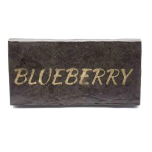 Brick of Blueberry Hash with a "Blueberry" gold stamp pressed into the surface, propped up on a clean white background